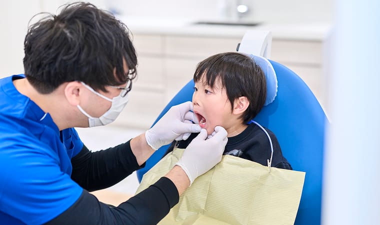 子供の口腔内をチェックする歯科医