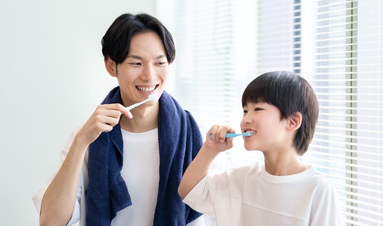 父と歯磨きをする小学生の男子