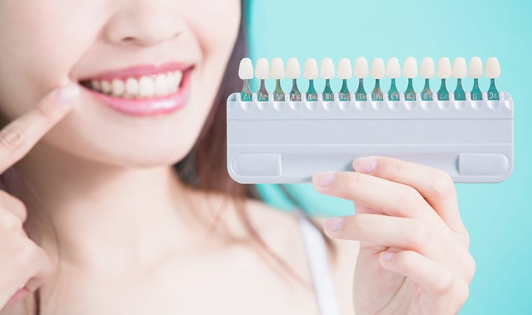 歯の白さのサンプルを比較する女性